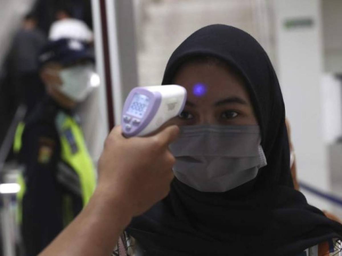 A medical team member checks a passenger's body temperature at a Mass Rapid Transit (MRT) station in Jakarta, Indonesia, Friday, March 6, 2020. Indonesia's COVID-19 Outbreak Mitigation spokesman Achmad Yurianto announced two new cases of COVID-19 infections on Friday, bringing the country's confirmed cases to four. (AP Photo/Tatan Syuflana)