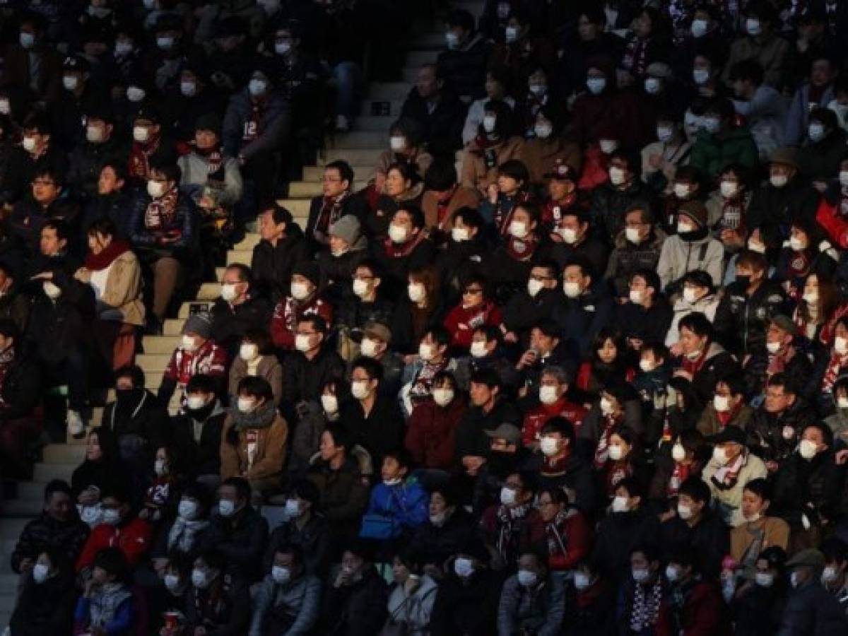 This picture taken on February 23, 2020 shows audience members wearing face masks at a J.League football match between Vissel Kobe and Yokohama F. Marinos in Kobe. - The Japanese government has urged people to avoid large gatherings, and Tokyo's government has cancelled some large public events over COVID-19 coronavirus fears that has now killed more than 2,400 people and spread around the world. (Photo by STR / JIJI PRESS / AFP) / Japan OUT