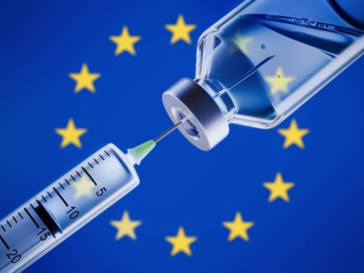Closeup of a syringe and vaccine in front of European flag background