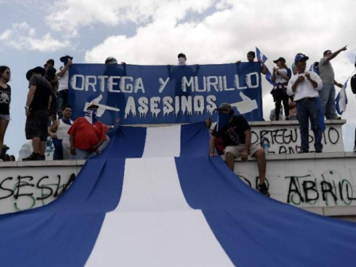 Protestantes anti-Gobierno sostienen el banner 'Ortega y Murillo asesinos', el 28 de julio de 2018. AFP PHOTO / MARVIN RECINOS