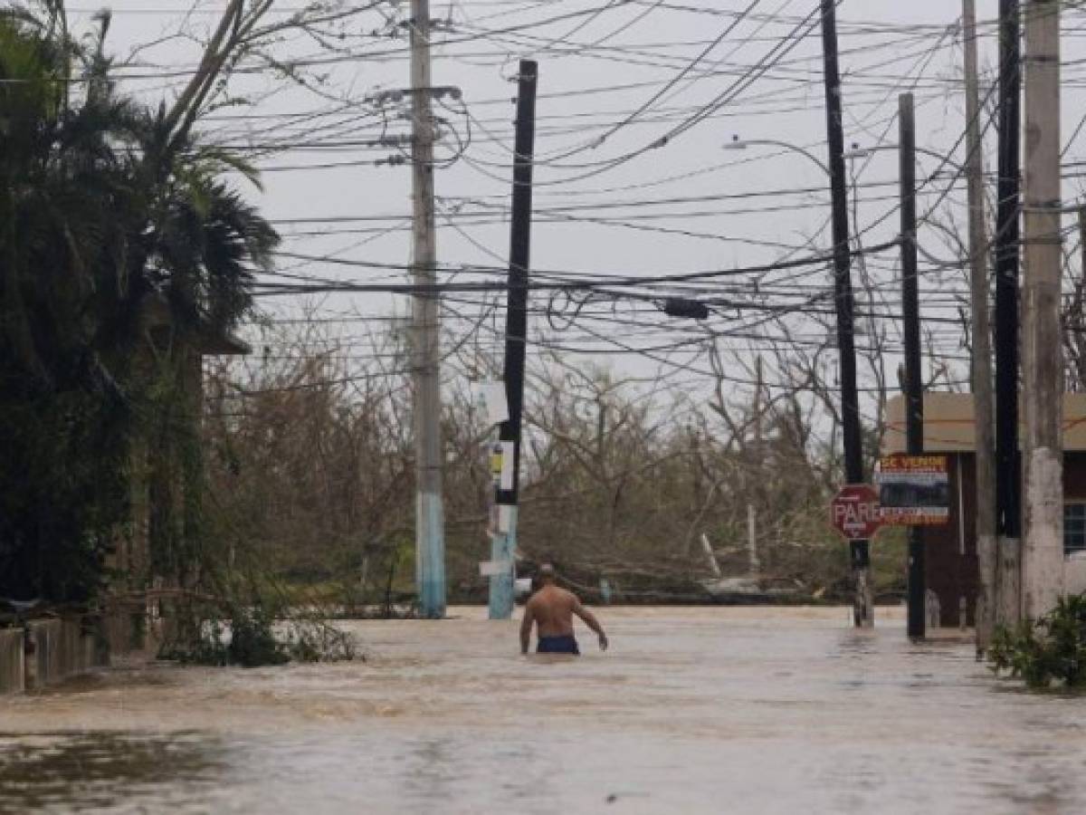A man wades through a flooded road as Hurricane Maria hits Puerto Rico in Fajardo, on September 20, 2017.Maria made landfall on Puerto Rico, pummeling the US territory after already killing at least two people on its passage through the Caribbean. The US National Hurricane Center warned of 'large and destructive waves' as Maria came ashore near Yabucoa on the southeast coast. / AFP PHOTO / Ricardo ARDUENGO