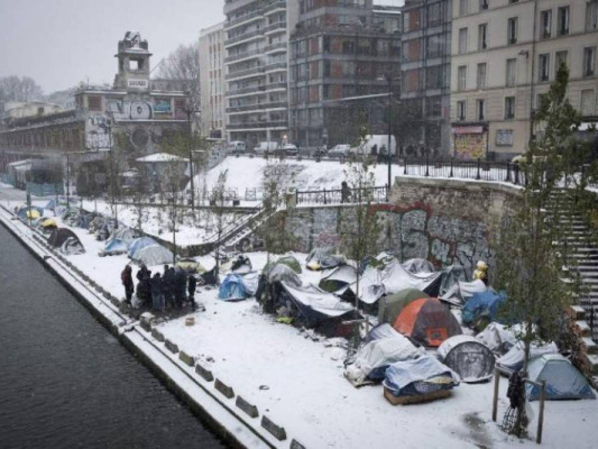 Afghan refugees gather in a makeshift camp as snow falls in Paris on February 9, 2018.The north-west of France has received fresh snowfall, affecting transport in the Ile-de-France region especially in Paris. / AFP PHOTO / JOEL SAGET