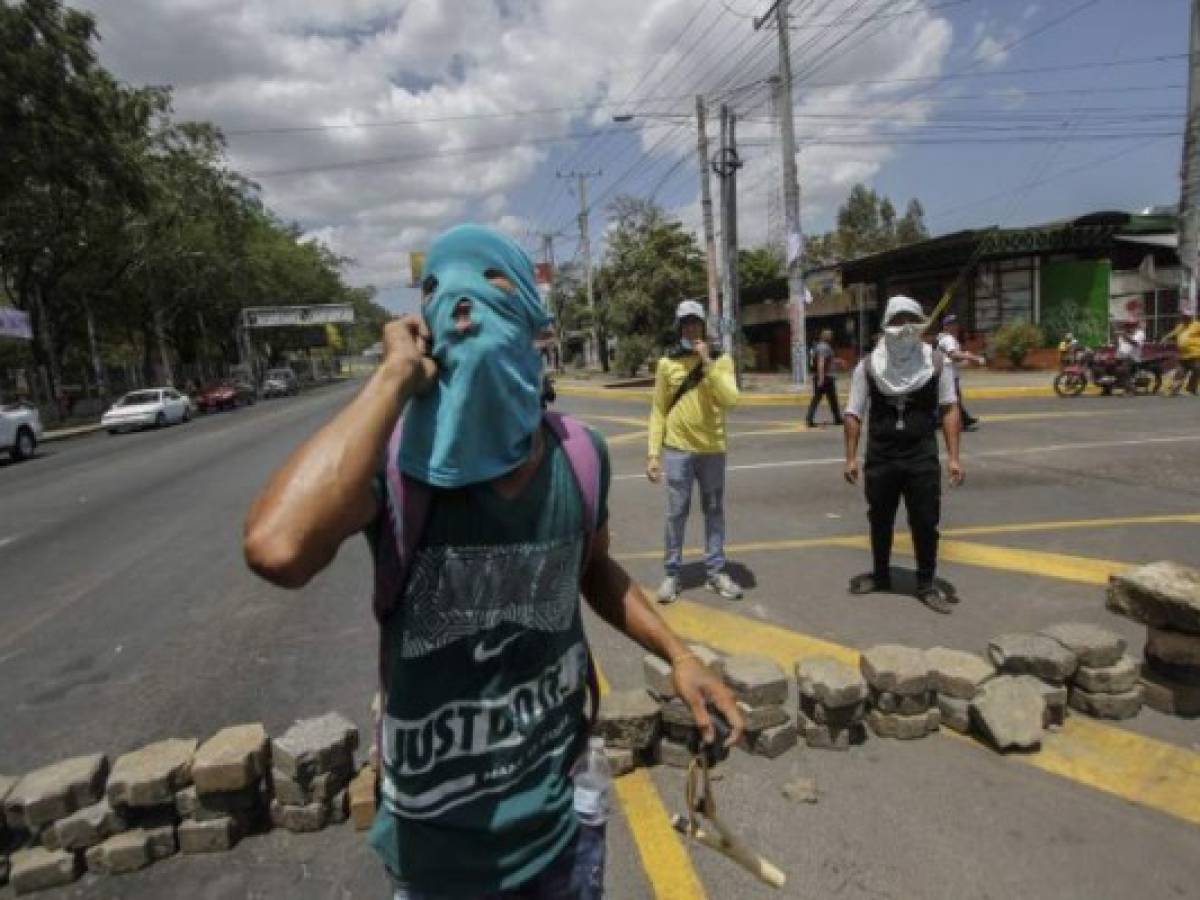Students block the street with stones in front of the Engineering University during a students' protest against government's reforms in the Institute of Social Security (INSS) in Managua on April 20, 2018.A protester and a policeman were killed in the Nicaraguan capital Managua after demonstrations over pension reform turned violent Thursday night, officials said. The deaths came after protests by both opponents and supporters of a new law, which increases employer and employee contributions while reducing the overall amount of pensions by five percent, rocked the capital for a second day. / AFP PHOTO / INTI OCON