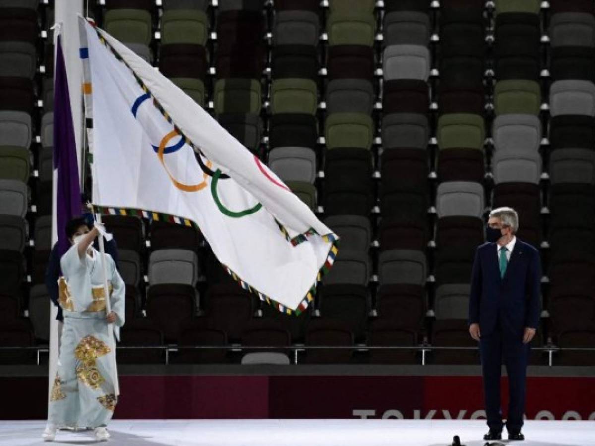 La gobernadora de Tokio, Yuriko Koike (izq.), Ondea la bandera olímpica del presidente del Comité Olímpico Internacional (COI), Thomas Bach, durante la ceremonia de clausura de los Juegos Olímpicos de Tokio 2020, el 8 de agosto de 2021 en el Estadio Olímpico de Tokio. (Foto de Jewel SAMAD / AFP)