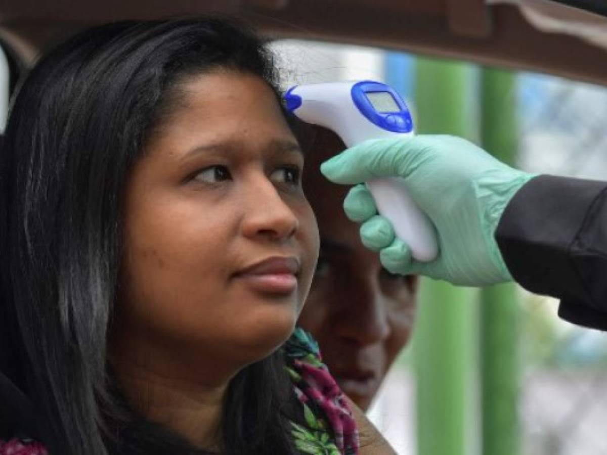 Un miembro del Servicio de Protección Institucional de Panamá mira la temperatura de una colaboradora del Palacio Presidencial como precaución del COVID-19. (Foto Luis ACOSTA / AFP)