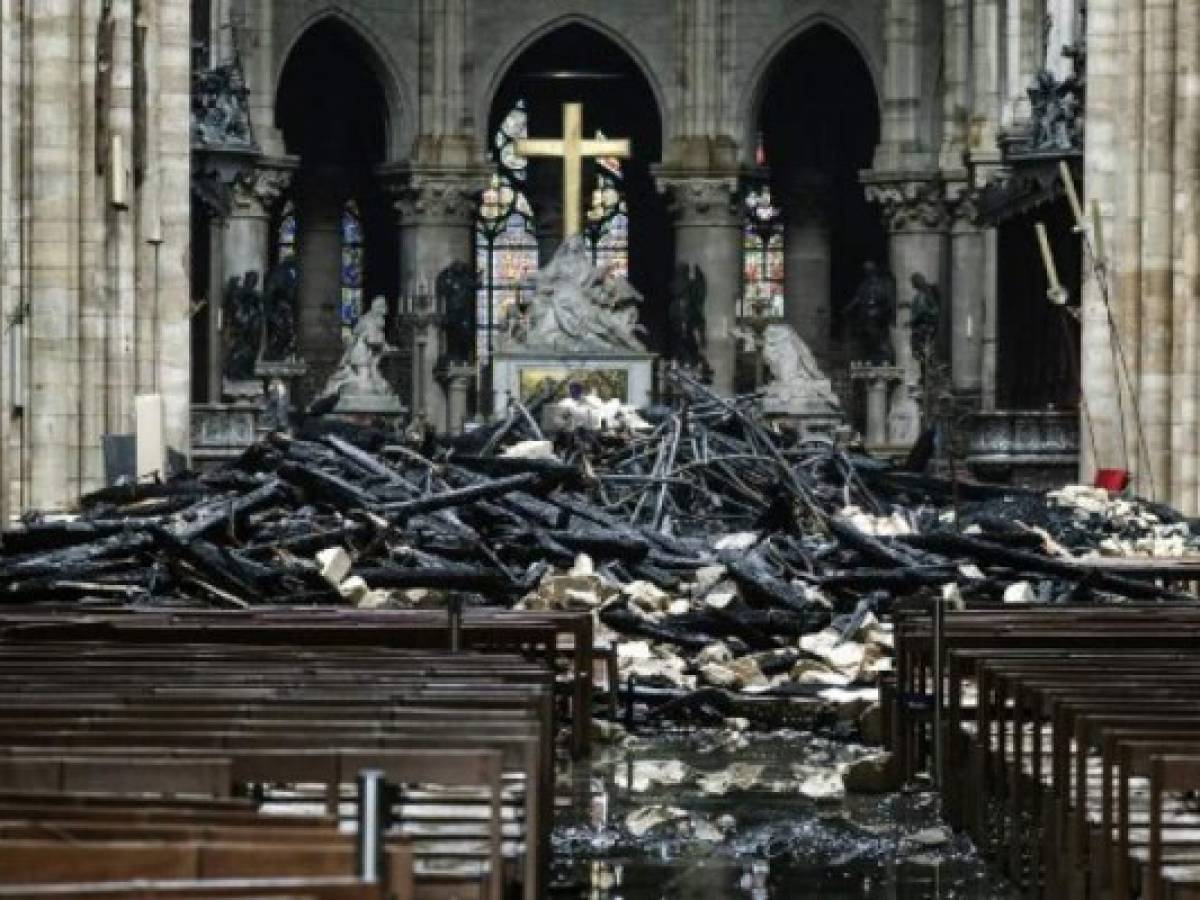 A picture taken on April 16, 2019 shows the altar surrounded by charred debris inside the Notre-Dame Cathedral in Paris in the aftermath of a fire that devastated the cathedral. - French investigators probing the devastating blaze at Notre-Dame Cathedral on April 15, 2019, questioned workers who were renovating the monument on April 16, as hundreds of millions of euros were pledged to restore the historic masterpiece. As firefighters put out the last smouldering embers, a host of French billionaires and companies stepped forward with offers of cash worth around 600 million euros ($680 million) to remake the iconic structure. (Photo by LUDOVIC MARIN / AFP)