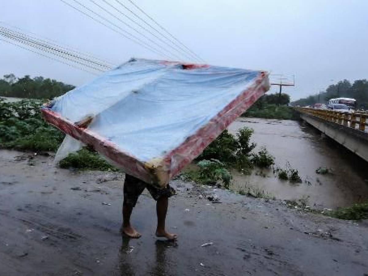 Un habitante sale de su casa mientras el río Chamelecón amenaza con desbordarse en el municipio de La Lima, departamento de Cortés, Honduras, debido a las lluvias que dejó la tormenta tropical Julia, el 9 de octubre de 2022. (Foto de Wendell ESCOTO / AFP)