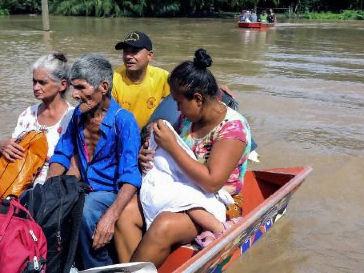 Personas afectadas por inundaciones tras el paso de la tormenta tropical Julia, son evacuadas en lancha, en el municipio de Choloma, departamento de Cortés, Honduras, el 10 de octubre de 2022. (Foto por Wendell ESCOTO/AFP)