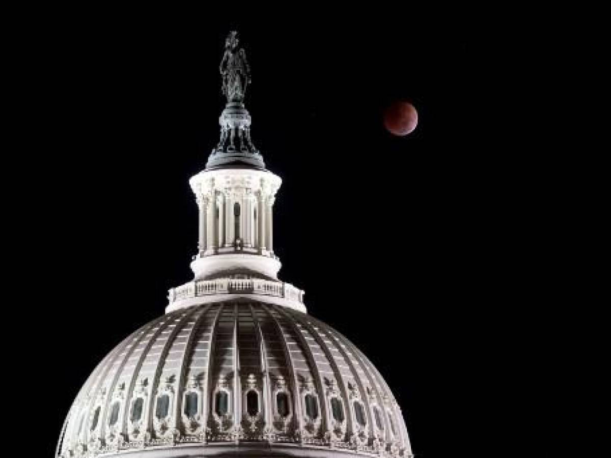 <i>La Luna se pone durante un eclipse lunar total detrás de la Estatua de la Libertad en la parte superior de la cúpula del Capitolio de EE. UU. en la mañana de las elecciones de mitad de período de EE. UU., en Washington, DC, el 8 de noviembre de 2022. (Foto de Stefani Reynolds / AFP)</i>