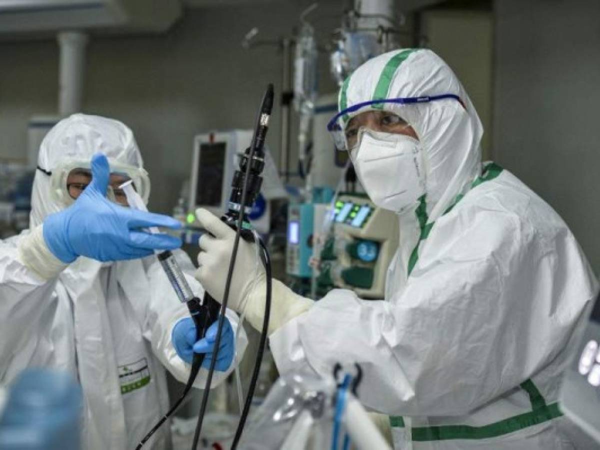 This photo taken on February 24, 2020 shows a doctor treating a patient infected by the COVID-19 coronavirus at a hospital in Wuhan in China's central Hubei province. - The new coronavirus has peaked in China but could still grow into a pandemic, the World Health Organization warned, as infections mushroom in other countries. (Photo by STR / AFP) / China OUT