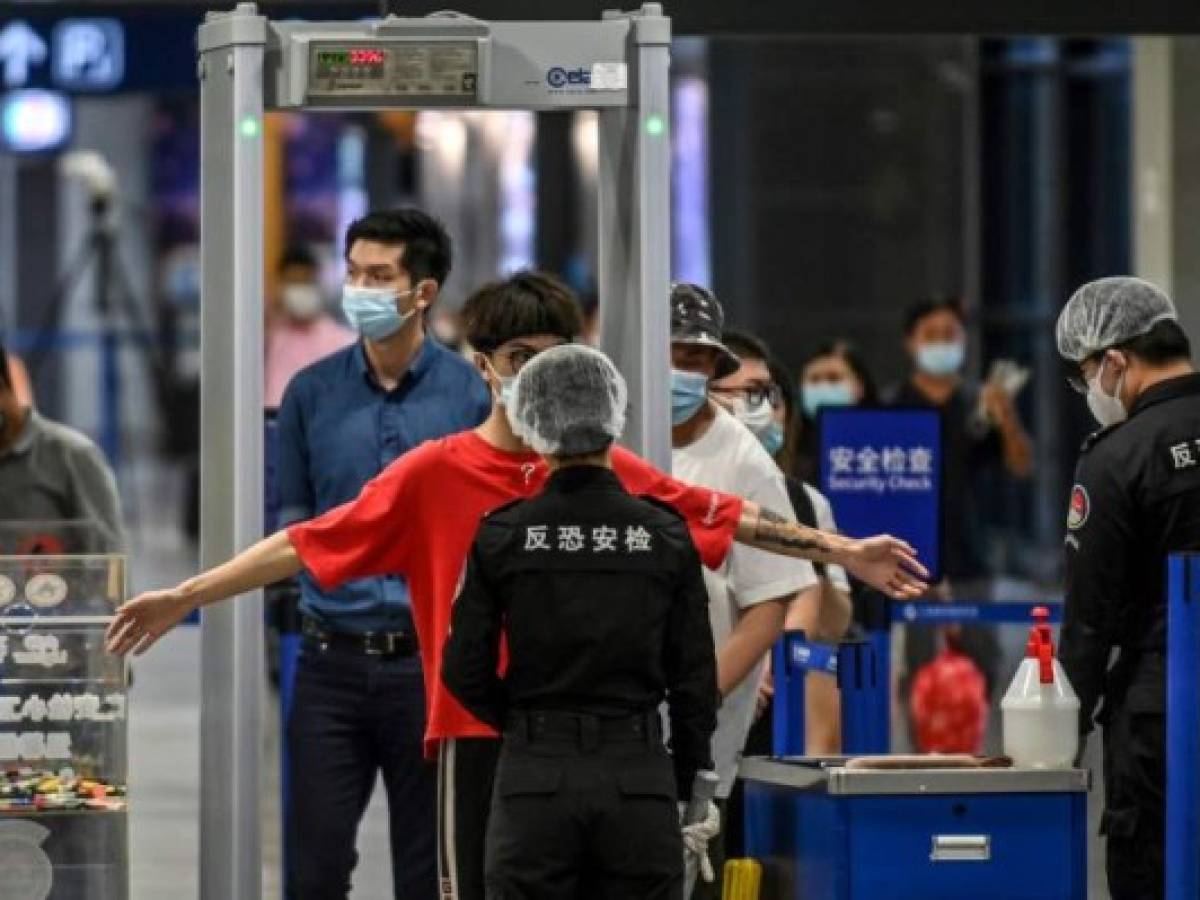Passengers wearing facemasks go through a check-point following preventive procedures against the spread of the COVID-19 coronavirus at one of the entries to the Pudong International Airport in Shanghai on June 11, 2020. (Photo by Hector RETAMAL / AFP)