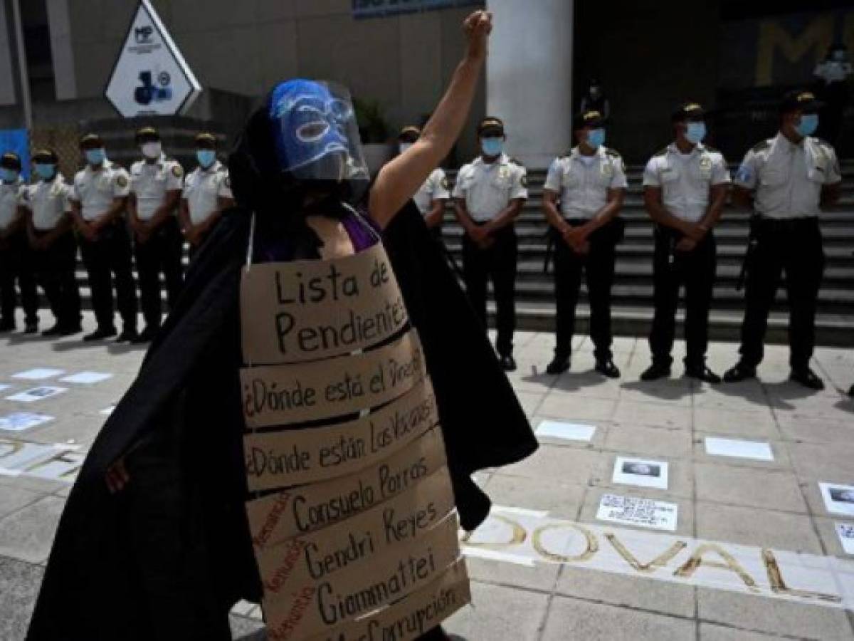 A demonstrator raises her fist in front of a line of police during a protest to demand the resignation of Guatemalan President Alejandro Giammattei and Guatemala's Attorney General Maria Consuelo Porras after Guatemala's Special Prosecutor against Impunity Juan Francisco Sandoval was dismissed, outside the Public Ministry's headquarters in Guatemala City on July 24, 2021. (Photo by Johan ORDONEZ / AFP)