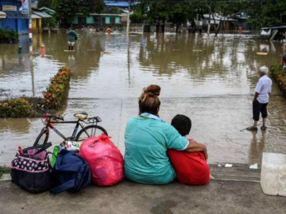 Honduran Blanca Rosa Calderon, who fled with her husband from the flooded La Guadalupe municipality with just two bikes and some clothes, remains with their son Guillermo at a square in the also flooded municipality of La Lima near San Pedro Sula in Honduras, on November 20, 2020, after the passage of Hurricane Iota. - Iota's death toll rose to 44 on Thursday after the year's biggest Atlantic storm unleashed mudslides, tore apart buildings and left thousands homeless across Central America, revisiting areas devastated by another hurricane just two weeks ago. (Photo by Orlando SIERRA / AFP)