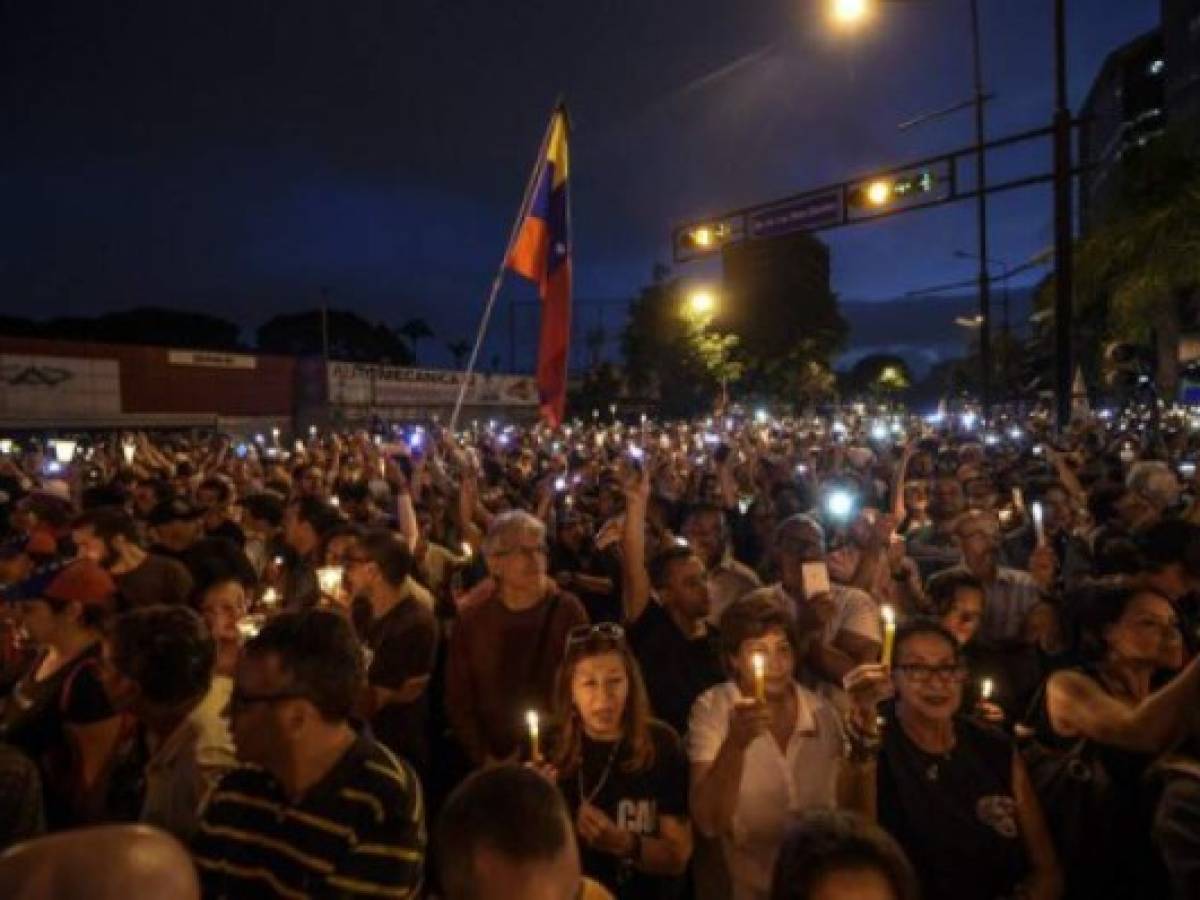 Opposition activists holding candles protest against the deaths of 43 people in clashes with the police during weeks of demonstrations against the government of Venezuelan President Nicolas Maduro, in Caracas on May 17, 2017. The United States warned on Wednesday at the United Nations that Venezuela's crisis was worsening and could escalate into a major conflict similar to Syria or South Sudan. / AFP PHOTO / JUAN BARRETO