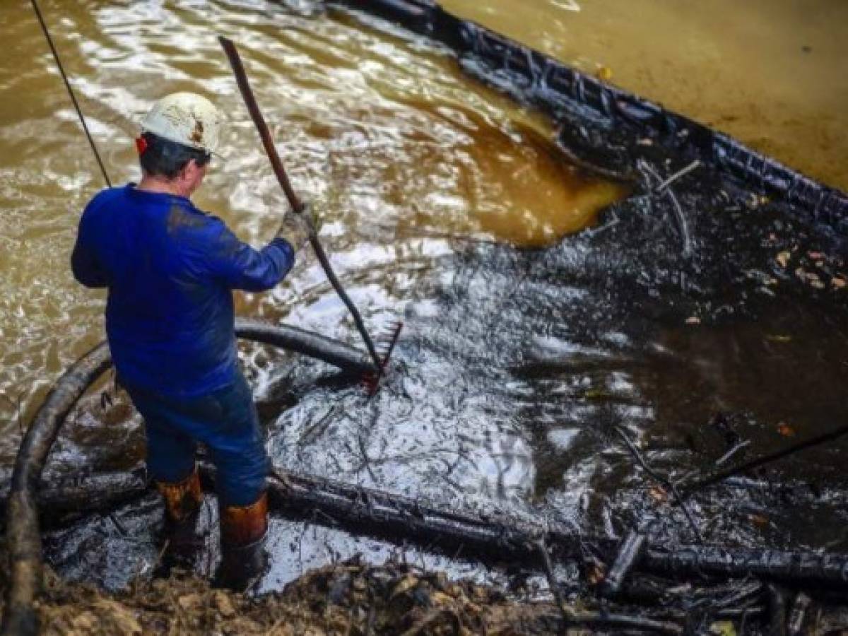 Workers of state owned oil company Ecopetrol, clean the Lizama river, which is affected by an oil leak in Barrancabermeja, Santander department, Colombia on March 26, 2018. The leakage of crude from an Ecopetrol inactive oil well, has generated an environmental crisis that completes 24 days in northern Colombia. / AFP PHOTO / str