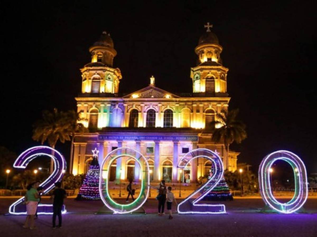 People walk in front of new-year decorations ahead of the celebration for year 2020 in Revolution Square in Managua on December 29, 2019. (Photo by INTI OCON / AFP)