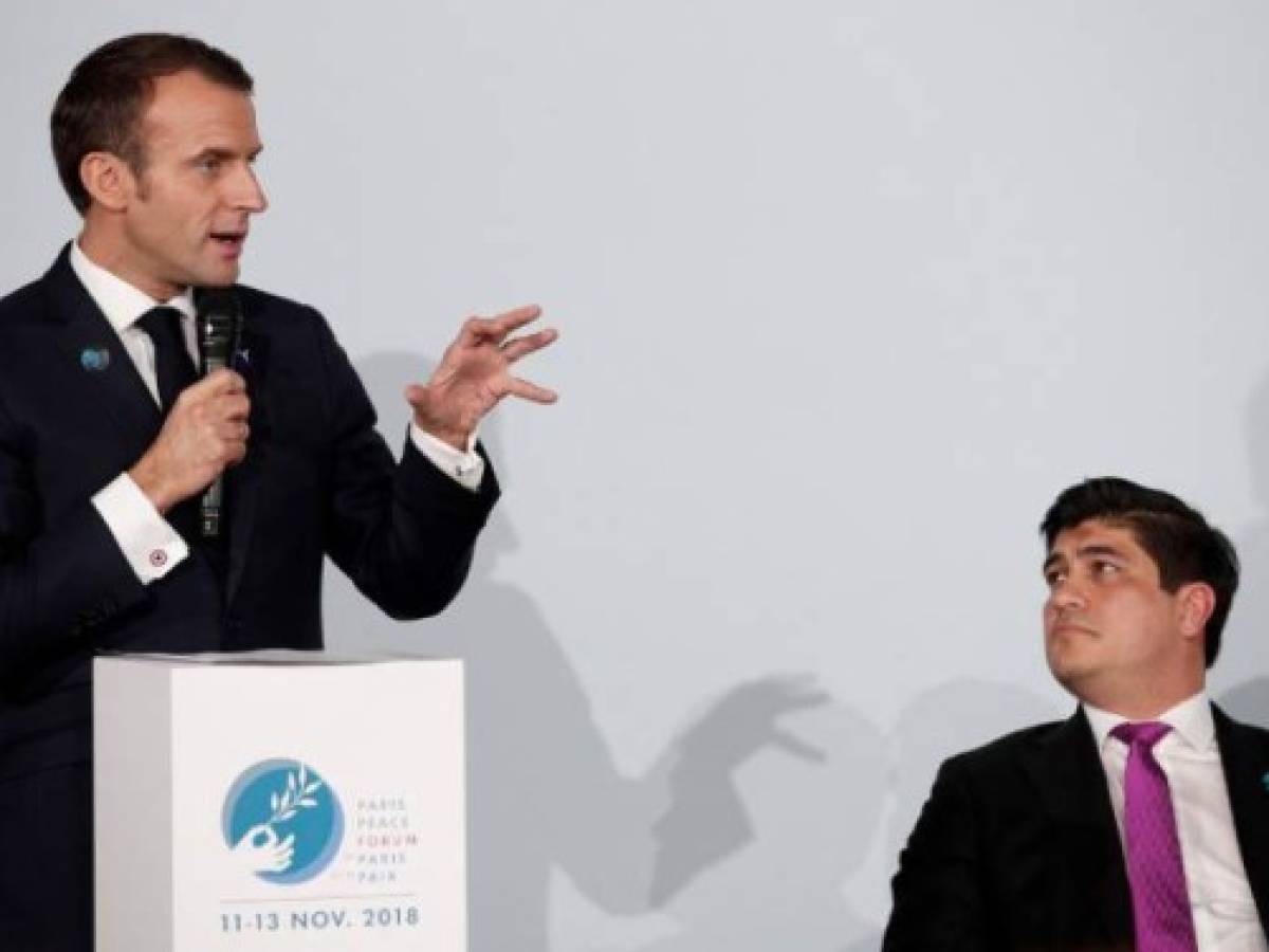 French President Emmanuel Macron is watched by President of Costa Rica Carlos Alvarado (R) as he delivers a speech ahead of the Paris Peace Forum at the Villette Conference Hall in Paris on November 11, 2018. - The Paris Peace Forum is a new annual event based on international cooperation and aimed at tackling global challenges and ensuring durable peace. (Photo by Yoan VALAT / POOL / AFP)