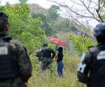 <i>Miembros de las Fuerzas Armadas de Honduras hacen guardia mientras las autoridades y el Centro de Medicina Legal y Ciencias Forenses buscan los restos de al menos 40 vecinos presuntamente ejecutados por la banda criminal Los Aguacates, en Lomas del Carmen, en San Pedro Sula, 180 kilómetros al norte de Tegucigalpa. , el 27 de mayo de 2024. FOTO AFP</i>
