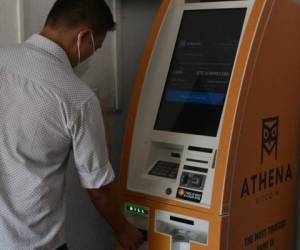 A man stands next to a Bitcoin ATM, after its inauguration by Athena Bitcoin Inc. at a shopping mall in San Salvador, on June 24, 2021. - The Bitcoin is an official currency in El Salvador. (Photo by MARVIN RECINOS / AFP)