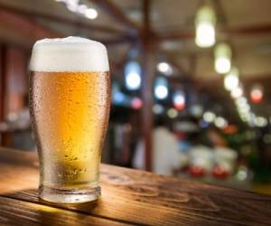 Glass of light beer on the glass bar counter.