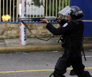 A riot police officer fires a weapon during clashes with students taking part in a protest in Managua on May 28, 2018. / AFP PHOTO / INTI OCON