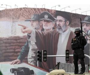 Fotografía de archivo de un miembro de las fuerzas de seguridad iraníes frente a una valla en la que aparecen el líder supremo iraní, Mojtaba Jamenei, y varios mandos militares iraníes. EFE/EPA/ABEDIN TAHERKENAREH
