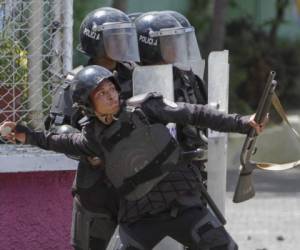 (FILES) In this file photo taken on April 19, 2018 a policeman throws a stone to students in front of the university of engineering who protest the government's reforms in the Institute of Social Security (INSS) in Managua. - After six months since anti-government demonstrations began in Nicaragua, initially protesting changes in the social security system, the unrest has ended up in a crisis that left more than 320 dead and a devastated economy. Even though a growing movement calls for the resignation of Ortega and Murillo, they have managed to stay is the power before an opposition without proposals to resume dialogue. (Photo by Inti Ocon / AFP)