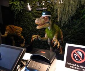 A robot dinosaur wearing a bellboy hats welcomes guests from the front desk at the Henn-na Hotel in Urayasu, suburban Tokyo on August 31, 2018. The reception at the Henn-na Hotel east of Tokyo is eeriely quiet until customers near the robot dinosaurs manning front desk. Their sensors detect motion and they bellow: 'Welcome.' It might be about the weirdest check-in experience possible, but that's exactly the point at the Henn-na ('Weird') chain, which bills itself as offering the world's first hotels staffed by robots. / AFP PHOTO / Kazuhiro NOGI