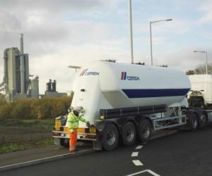 Driver, lorry and the Rugby Cement Plant as backdrop.Rugby, England. CEMEX UK.UK01P 0001