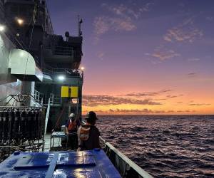 <i>Puesta de sol a bordo del Thomas G. Thompson, un buque de investigación operado por la Universidad de Washington y equipado para viajes oceánicos. El instrumento que se ve a la izquierda es un muestreador de agua que puede recoger muestras a diferentes profundidades. Crédito: Kathy Newer/Universidad de Washington</i>