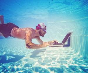 Man using a laptop underwater, in a swimming pool
