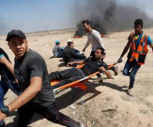 Palestinos cargan un protestante herido durante la marcha contra el Ejército de Israel en la frontera de la Franja de Gaza. AFP PHOTO / Thomas COEX