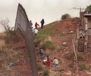 (ARCHIVO) Un grupo de presuntos emigrantes mexicanos caminan junto a la valla fronteriza separando México de Estados Unidos el 13 de febrero de 1995, del lado mexicano frente a Nogales, Arizona. AFP PHOTO / CHRIS WILKINS