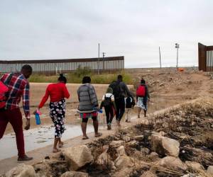 <i>ARCHIVO. Familias haitianas caminan a través de una brecha en el muro fronterizo entre Estados Unidos y México el 7 de diciembre de 2021 hacia Yuma, Arizona. En muchos casos, los funcionarios de inmigración mexicanos permiten a las familias migrantes con madres embarazadas, consideradas altamente vulnerables, dirigirse a la frontera de Estados Unidos, donde pueden solicitar asilo. FOTO John Moore/Getty Imagesvía AFP</i>