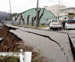 <i>La gente se encuentra junto a grandes grietas en el pavimento después de ser evacuada a una calle en la ciudad de Wajima, prefectura de Ishikawa, el 1 de enero de 2024, después de que un gran terremoto de magnitud 7,5 sacudiera la región de Noto en la prefectura de Ishikawa por la tarde. FOTO YUSUKE FUKUHARA / YOMIURI SHIMBUN / AFP</i>