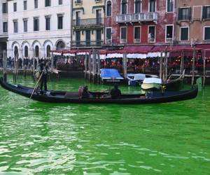 <i>Una góndola navega por el Gran Canal después de que activistas de Extinction Rebellion (XR) vertieran fluoresceína cerca del puente de Rialto en Venecia para hacer que el agua fuera fluorescente durante una protesta contra el 'fracaso' de la COP28 sobre el clima. FOTO Marco SABADÍN / AFP</i>