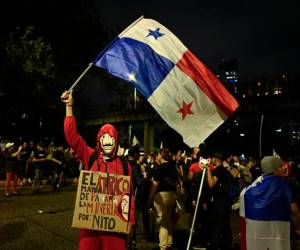 Un manifestante con una máscara y un traje de Money Heist ondea una bandera panameña durante una marcha contra el contrato gubernamental con la compañía minera canadiense First Quantum y su filial Minera Panamá en la ciudad de Panamá el 27 de octubre de 2023. FOTO LUIS ACOSTA / AFP