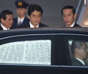 El primer ministro japonés, Shinzo Abe, al centro, aborda un coche en el aeropuerto tokiota de Haneda. (Foto: AFP)