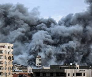 <i>Una columna de humo se eleva sobre los edificios de la ciudad de Gaza el 7 de octubre de 2023 durante un ataque aéreo israelí. Se informó que al menos 70 personas murieron en Israel, mientras que las autoridades de Gaza publicaron un número de muertos de 198 en la escalada más sangrienta del conflicto más amplio desde mayo de 2021, con cientos más heridos en ambos lados. FOTO MAHMUD HAMS / AFP</i>