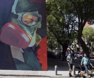 People walk next to a coronavirus-related mural at the Roma neighborhood in Mexico City, on June 9, 2020, during the novel COVID-19 pandemic. (Photo by ALFREDO ESTRELLA / AFP)