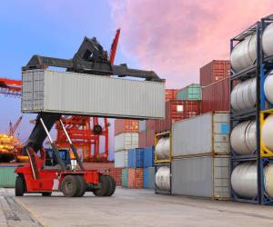 forklift handling the container box at dockyard with harbour background