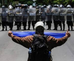 Un manifestante muestra una bandera de Nicaragua a las fuerzas policiales durante la protesta del 16 de septiembre del 2018 donde miles de personas pidieron la salida de Daniel Ortega.INTI OCON AFP/Getty Images