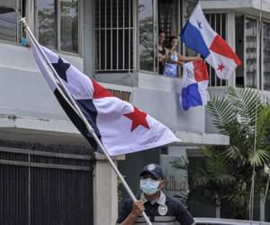 A police officer wearing a mask carries a Panamanian national flag as members of the force cheer up the neighbourhood with dances and songs during a lockdown to help contain the COVID-19 novel coronavirus pandemic, in Panama City on June 28, 2020. - The total number of global COVID-19 infections has now surpassed 10 million, according to an AFP tally at 0930 GMT on Sunday based on official sources, with at least 498,779 people killed worldwide so far according to the count. (Photo by Luis ACOSTA / AFP)