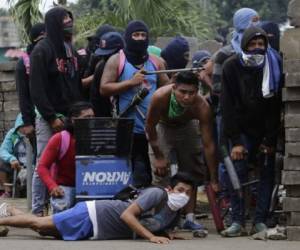 Anti-government demonstrators take cover behind a barricade, during clashes with riot police and members of the Sandinista youth, in Masaya some 35 km from Managua on June 19, 2018.Nicaraguan police and pro-government paramilitaries moved to reassert control over the city of Masaya by force Tuesday after residents of the opposition bastion declared themselves in rebellion against President Daniel Ortega. / AFP PHOTO / INTI OCON