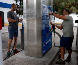 <i>FOTO CLEARWATER BEACH, FLORIDA - 29 DE AGOSTO: Bilal Kefel (L) y Nazih Taggeddine envuelven con celofán una bomba de gasolina para evitar que sea dañada por la lluvia del huracán Idalia cuando pasa frente a la costa el 29 de agosto de 2023 en Clearwater Beach, Florida. Se pronostica que el huracán Idalia toque tierra en la costa del Golfo de Florida el miércoles por la mañana. Joe Raedle/Getty Images/AFP</i>