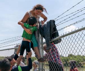 <i>(ARCHIVOS) Una madre ayuda a su hijo a cruzar la cerca de alambre de púas en Eagle Pass, Texas, después de cruzar a Estados Unidos desde México el 25 de agosto de 2023. FOTO SUZANNE CORDEIRO / AFP</i>