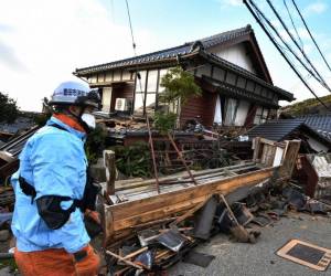 <i>Los bomberos inspeccionan casas de madera derrumbadas en Wajima, prefectura de Ishikawa, el 2 de enero de 2024, un día después de que un gran terremoto de magnitud 7,5 sacudiera la región de Noto en la prefectura de Ishikawa por la tarde. FOTO Kazuhiro NOGI/AFP</i>