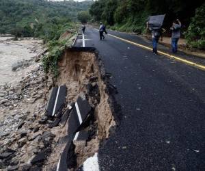 La gente pasa por parte de una carretera que fue arrasada en la comunidad del Kilómetro 42, cerca de Acapulco, estado de Guerrero, México, tras el paso del huracán Otis, el 25 de octubre de 2023 .RODRIGO OROPEZA / AFP