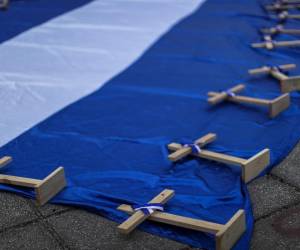 <i>Se ven cruces encima de una bandera de Nicaragua durante una manifestación para conmemorar el Día Nacional de la Paz de Nicaragua, que se celebra en el país el 19 de abril. FOTO José Cordero / AFP</i>