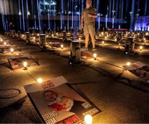 <i>Un hombre se encuentra entre carteles de rehenes secuestrados por militantes palestinos durante el ataque del 7 de octubre y actualmente retenidos en la Franja de Gaza, colocados junto a bombillas y focos como parte de una instalación que consta de 224 pilares de luz erigidos por la municipalidad de Jerusalén como homenaje a Los rehenes fueron capturados frente al estadio Teddy de Jerusalén el 26 de octubre de 2023. FOTO AHMAD GHARABLI / AFP</i>